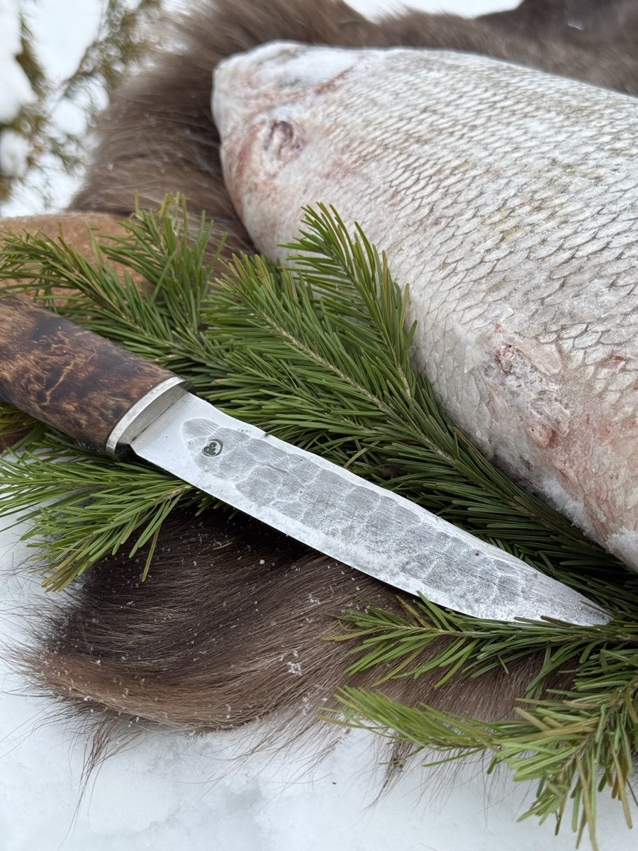 Нож и целая мороженая рыба на мехе